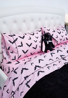 a bed with pink and black bats on the sheets, pillows and pillowcases