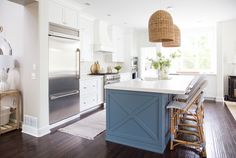 a kitchen with white cabinets and blue island