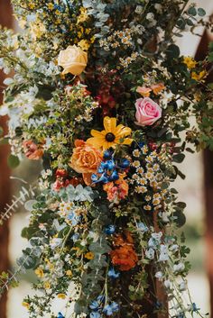 an arrangement of flowers and greenery hanging from the ceiling