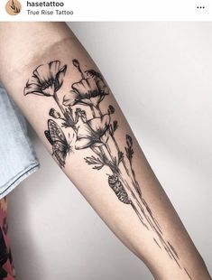 a woman's arm with flowers and butterflies tattooed on the side of her arm