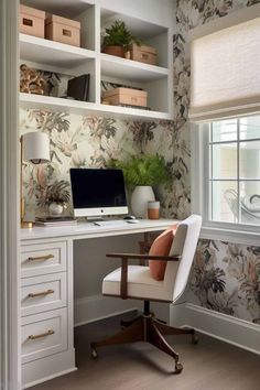 a desk with a computer on top of it in front of a flowered wallpaper