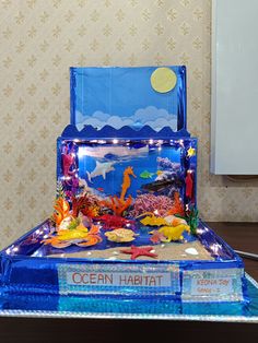 an ocean habitat made out of plastic and cardboard with lights on it, sitting on a table in front of a wall