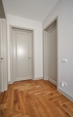 an empty room with wooden floors and two doors on the opposite side of the room