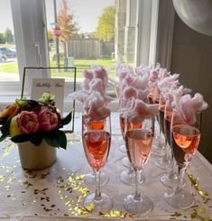 there are many wine glasses on the table with flowers in them and confetti