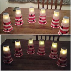 there are many red and white striped cones on the table with light up candles in them