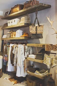 an image of a closet with clothes and handbags on the shelves in front of it