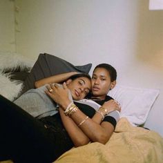 a man and woman laying on top of a bed next to each other with their arms around each other