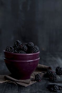 a purple bowl filled with blackberries on top of a table