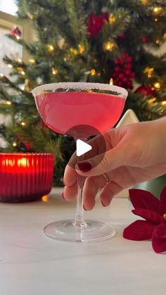 a person holding a wine glass in front of a christmas tree