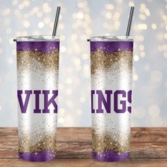 two purple and gold glittered tumblers with the word viking on them sitting on a wooden table