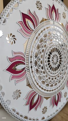 a decorative white plate with pink and gold designs on the rim, sitting on a table