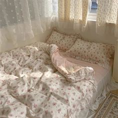 an unmade bed sitting in front of a window