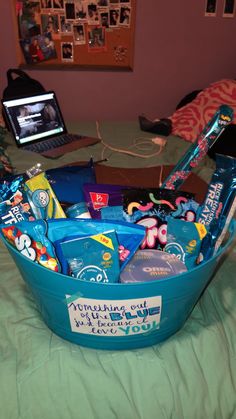 a blue tub filled with lots of items on top of a bed