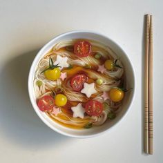 a white bowl filled with noodles and vegetables next to chopsticks