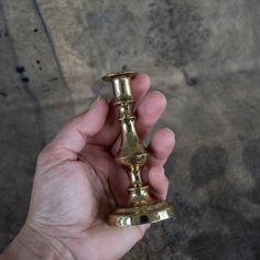 a person holding a gold colored metal object in their left hand and the other hand is pointing towards it