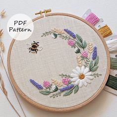 a close up of a cross stitch pattern with flowers and a bee in the middle