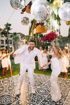 a man and woman dancing on a dance floor with disco balls hanging from the ceiling