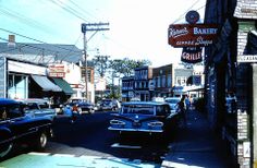 an old fashioned street with cars parked on the side