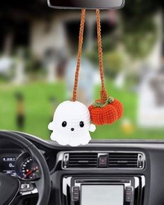 a car dashboard with a stuffed ghost hanging from the dash board