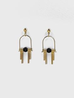 These Art Deco inspired earrings feature sleek, modern design elements, highlighting the contrast between the rich, dark hues of the black, semi precious Agate stone and the radiant golden brass. Each earring boasts a distinctive arched geometric shape inspired by the Art Deco style, lending a sense of elegance and sophistication.  The stepped cut brass fringe creates movement and shine and adds to the uniqueness and contemporary design.  Their minimalist yet bold design embodies a harmonious balance between simplicity and intricacy, making them a versatile accessory suitable for both formal occasions and everyday wear. Each earring is finished with a brass ball stud with stainless steel post. Approximate measurements- 4.5 long 1.5cms wide All Set Theory Jewellery comes with care instructi Modern Black Jewelry With Matching Earrings, Modern Onyx Earrings With Black Enamel, Modern Gold Earrings With Black Enamel, Modern Metal Linear Earrings For Evening, Modern Gold Onyx Earrings, Black Minimalist Pierced Earrings, Modernist Black Earrings For Gift, Modernist Black Earrings As Gift, Modern Onyx Drop Earrings