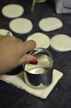 a person is making pizza dough on a table with circles in the background and one hand holding a ring