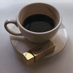 a cup of coffee and a gold bar on a saucer