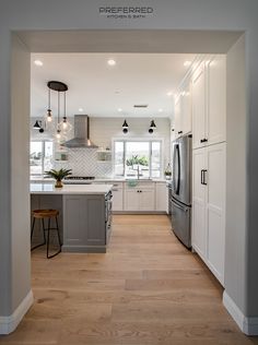 an open kitchen with white cabinets and wood flooring is pictured in this image from the front door