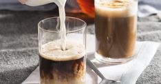 a person pouring milk into a glass on top of a napkin next to a cup