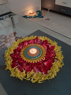 a candle is lit in the center of a circular arrangement of flowers and leaves on a table