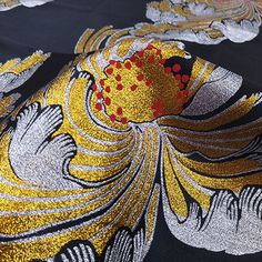 an image of a black and gold fabric with red flowers on the side, close up