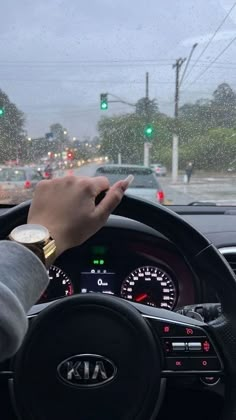 a person is driving in the rain with their hand on the steering wheel