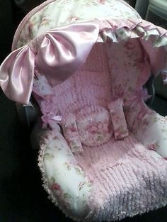 a baby's car seat with pink flowers and bows on the top, sitting in a chair