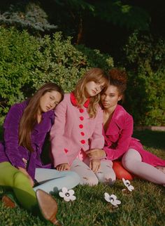 three young women sitting on the grass together