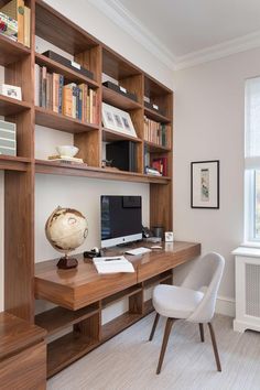 a desk with a computer on top of it in front of a book shelf filled with books