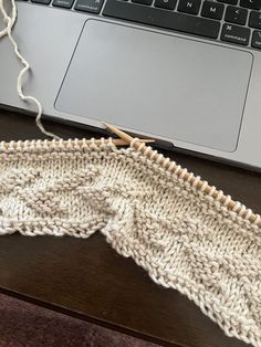 a close up of a knitted cloth next to a laptop