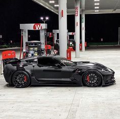 a black sports car parked in front of a gas station