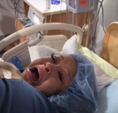 a woman laying in a hospital bed with her mouth open