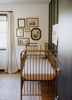 a baby's crib in the corner of a room with pictures on the wall