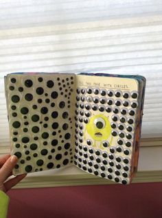 an open book with black and white polka dots on it, in front of a window