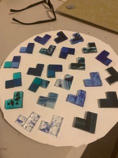 a white table topped with lots of blue and black pieces of glass on top of it