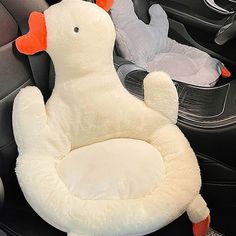 a stuffed duck sitting in the middle of a car seat with its head turned to the side