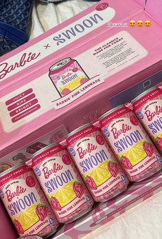 six cans of soda are in a pink box