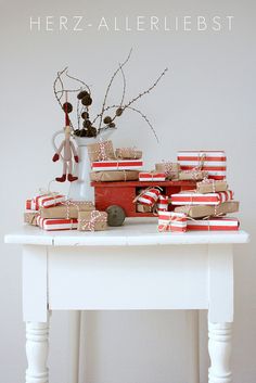 a white table topped with lots of boxes and wrapped presents on top of each other