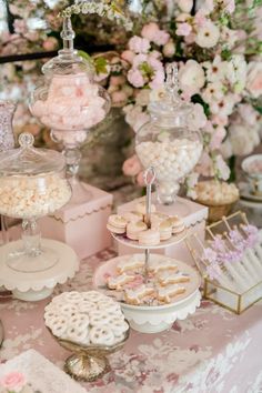 a table topped with lots of desserts and candies on top of tables covered in pink flowers