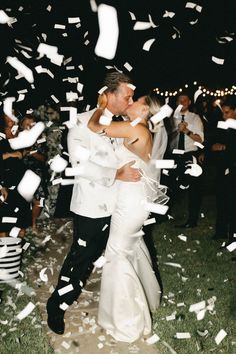 a newly married couple kissing under confetti