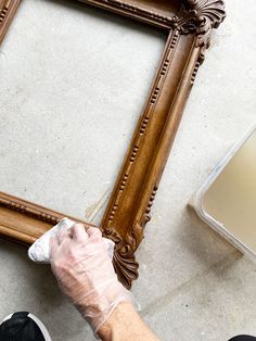 a person in white gloves waxing a wooden frame