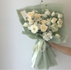 a bouquet of white flowers is being held by someone's hand with a tag on it