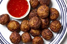 a white plate topped with meatballs next to a bowl of ketchup