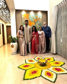 a group of people standing next to each other in front of a flower design on the floor