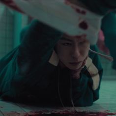 a man laying on the ground with blood all over his face and headphones hanging from his ears